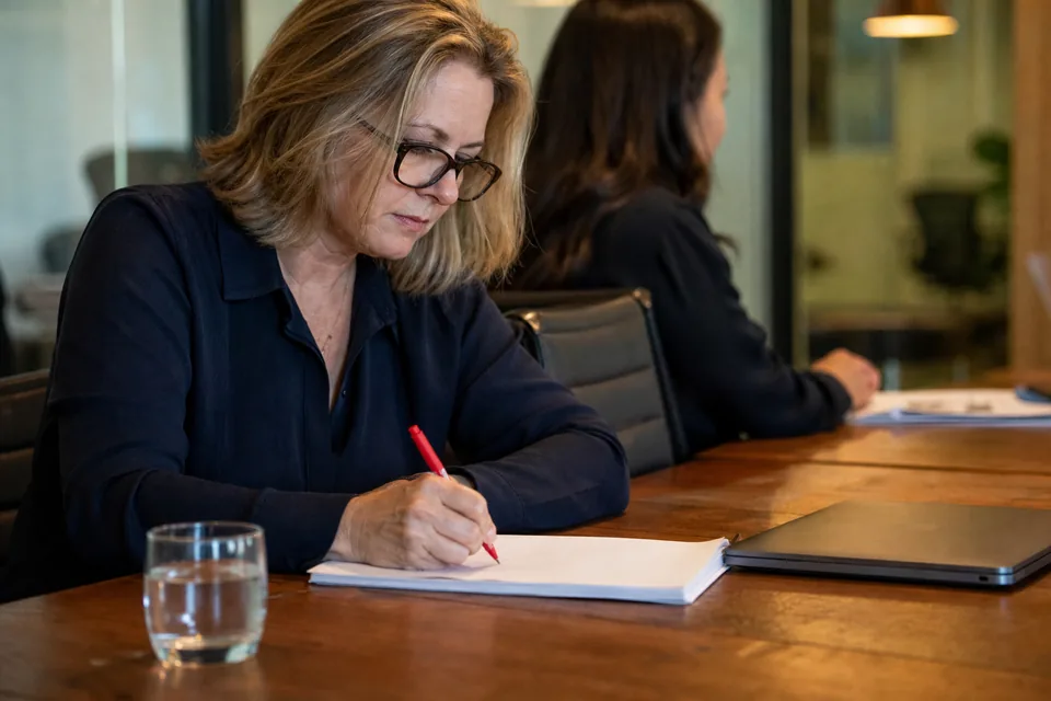 HR director at a conference table marking up a vendor contract with a pen