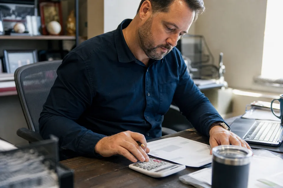 HR coordinator calculating a quiz software subscription cost at his desk