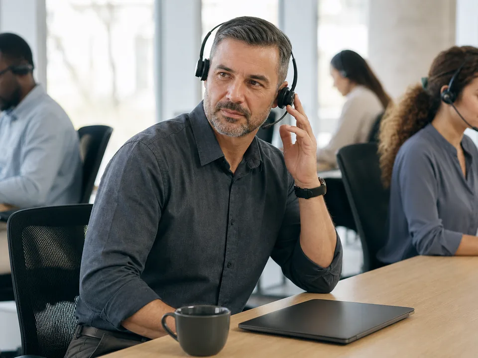 Contact center team lead with a headset listening to a recorded applicant answer