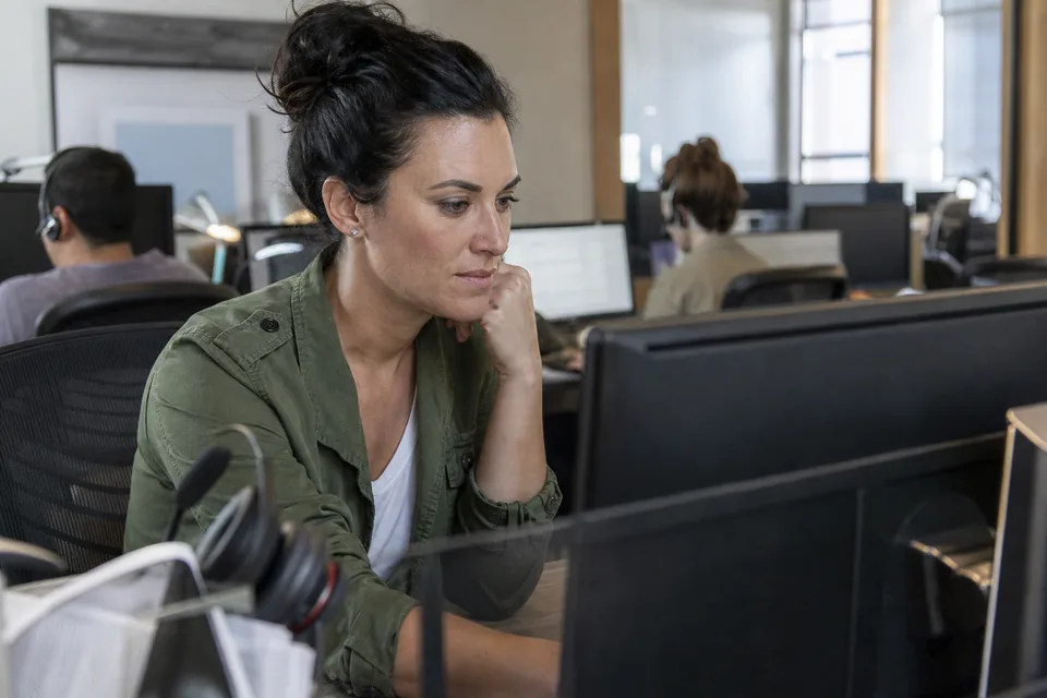 Customer support team lead reviewing applicant answers on a monitor in a small contact center